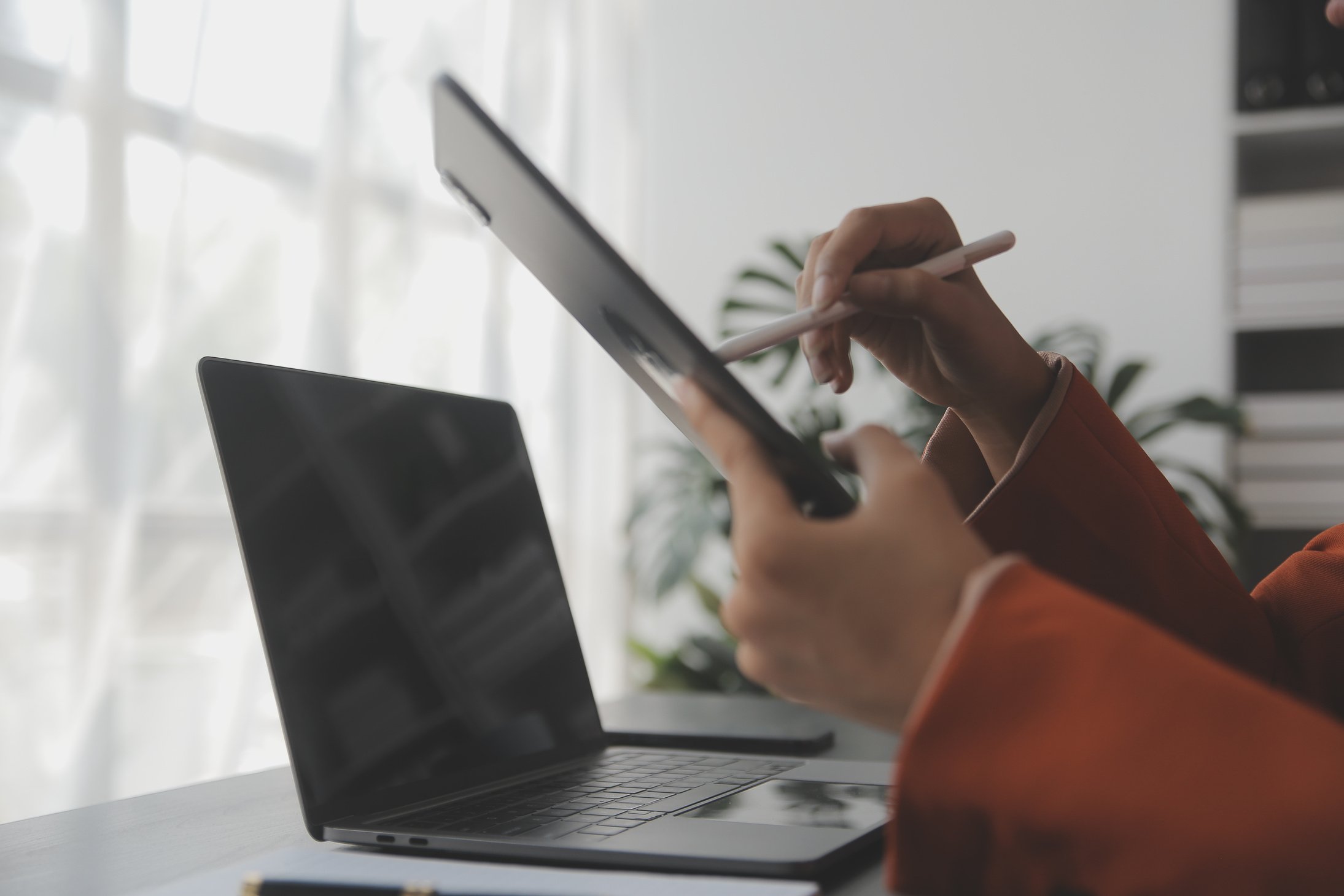 Portrait of Young Asian woman hand freelancer is working her job on computer tablet in modern office. Doing accounting analysis report real estate investment data, Financial and tax systems concept.